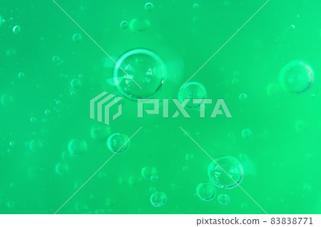 Texture of transparent green gel with air bubbles and waves on white background. Concept of skin moisturizing, body care and prevention of covid19. Liquid beauty product closeup. Backdrop, flat lay 83838771
