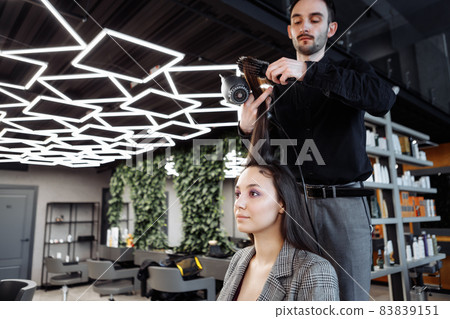 The master does hair styling in a beauty salon. Young woman preparing for a date. The master does hair styling in a beauty salon. Young woman preparing for a date. 83839151