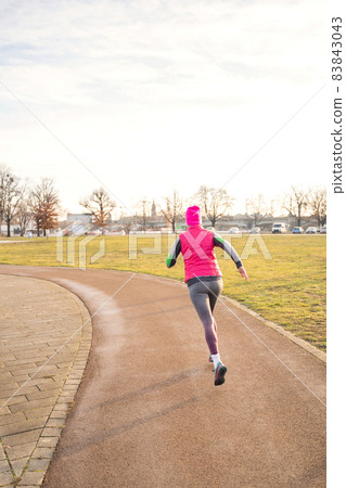 Young fit caucasian woman in fitness clothes running on track in park on sunrise Young fit caucasian woman in fitness clothes running on track in park on sunrise 83843043