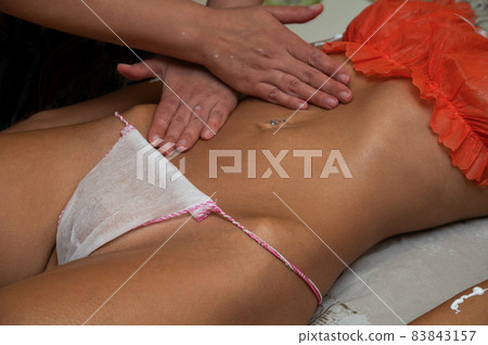 Woman getting belly massage with oil and scrub in spa salon Woman getting belly massage with oil and scrub in spa salon 83843157