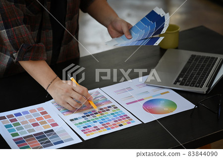 Graphic designer working with color swatches on office desk. 83844090