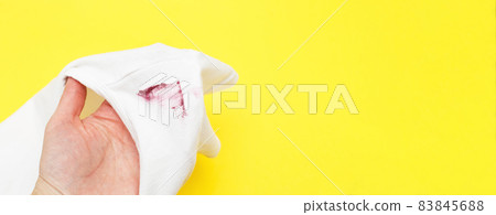 female hand holding white shirt with red lipstick stain on yellow background female hand holding white shirt with red lipstick stain on yellow background 83845688