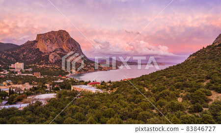 Aerial panoramic view of mount Falcon lit by pink sunset in Novyi Svit during autumn season. Sudak, the Republic of Crimea Aerial panoramic view of mount Falcon lit by pink sunset in Novyi Svit during autumn season. Sudak, the Republic of Crimea 83846727