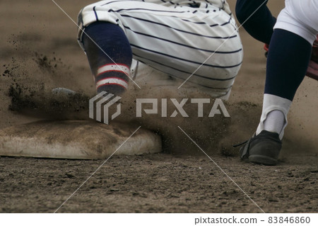 A baseball player who tries to steal a base and slips into the base during a baseball game 83846860