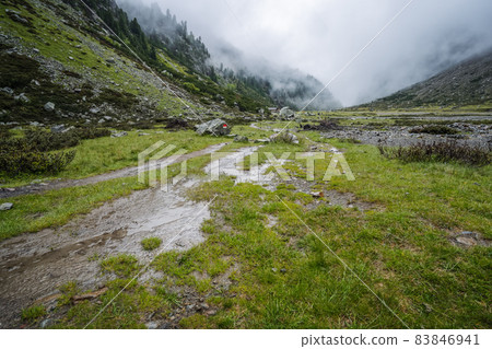 Summer view of alpine mountain valley with winding stream and glacial lake. Sulzenau Alm, Stubai Alps, Austria Summer view of alpine mountain valley with winding stream and glacial lake. Sulzenau Alm, Stubai Alps, Austria 83846941