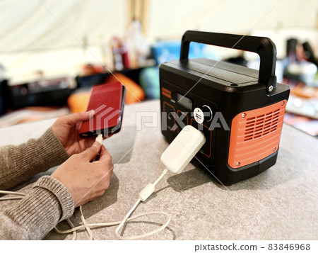 一個女人的手用帳篷裡的便攜式電源給智能手機充電 83846968