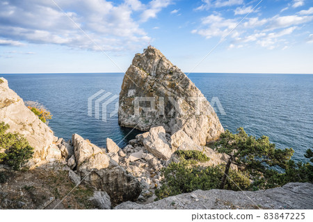 Rock Diva framed by autumnal yellow leaves in Simeiz, Crimea. Beautiful black sea shore seascape with mountain cliff, main nature landmark Rock Diva framed by autumnal yellow leaves in Simeiz, Crimea. Beautiful black sea shore seascape with mountain cliff, main nature landmark 83847225