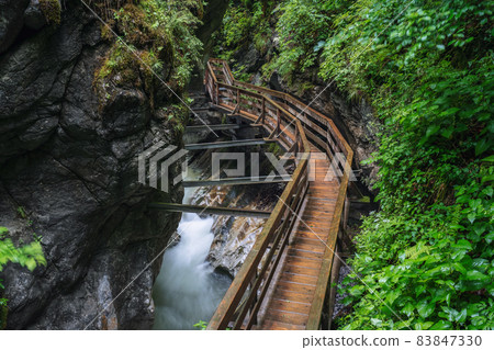 Wooden hike trail path inside a gorge with bue mountain river, Sigmund Thun Klamm, Kaprun, Austria 83847330