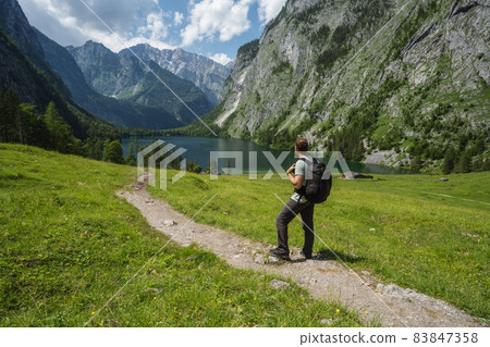 Man with backpack on hiking trail enjoying Hinterer Gosausee, Salzkammergut. Austria 83847358