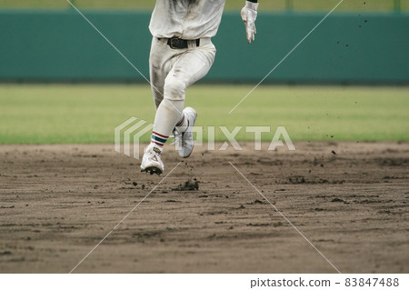 A baseball player who runs at full speed aiming for the next base during a baseball game 83847488