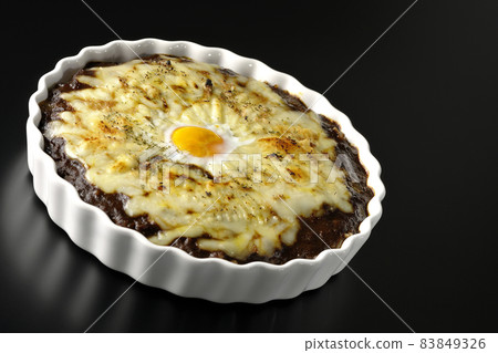 Photographed a grilled curry with plenty of melting cheese and eggs on a black background Photographed a grilled curry with plenty of melting cheese and eggs on a black background 83849326