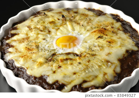 Photographed a grilled curry with plenty of melting cheese and eggs on a black background Photographed a grilled curry with plenty of melting cheese and eggs on a black background 83849327