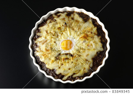 A bird's-eye view of grilled curry with plenty of melting cheese and eggs on a black background 83849345