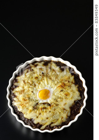 A bird's-eye view of grilled curry with plenty of melting cheese and eggs on a black background 83849349