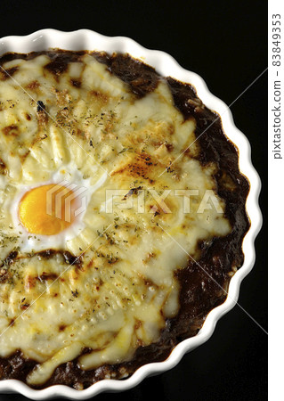 A bird's-eye view of grilled curry with plenty of melting cheese and eggs on a black background 83849353