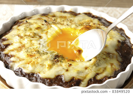Eat a grilled curry egg with plenty of melted cheese and eggs on it with a spoon. Eat a grilled curry egg with plenty of melted cheese and eggs on it with a spoon. 83849520
