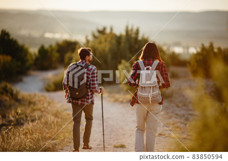 Portrait of happy young couple having fun on their hiking trip. Caucasian and asian hiker couple enjoying themselves on summer vacation. Portrait of happy young couple having fun on their hiking trip. Caucasian and asian hiker couple enjoying themselves on summer vacation. 83850594