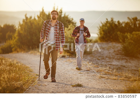 two men hikers enjoy a walk in nature, sunset time in summer two men hikers enjoy a walk in nature, sunset time in summer 83850597