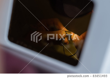 The technician solders the metal frame of the glasses. 83851493