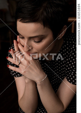 Pretty young woman portrait with her clasped fingers hands close to face, vintage styled 83851694