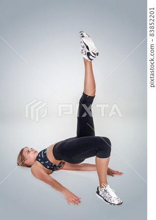 Beautiful young woman doing exercises on the floor to strengthen Beautiful young woman doing exercises on the floor to strengthen 83852201