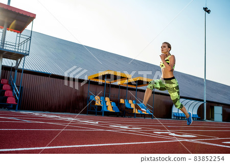 A female athlete runs along the treadmill. Sport background A female athlete runs along the treadmill. Sport background 83852254