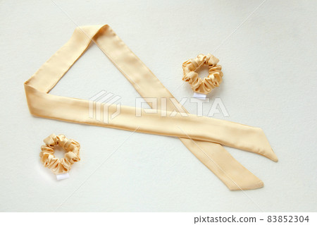 golden silk scrunchy flat lay on white. Hairdressing tools and accessories. luxury ladyes hair scarf 83852304