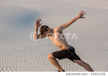 Fit man running fast on the sand. Powerful runner training outdoor on summer. 83852308