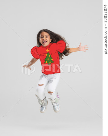 Contemporary art collage of happy child, girl jumping in red drawn sweater isolated over white background. Concept of winter holiday Contemporary art collage of happy child, girl jumping in red drawn sweater isolated over white background. Concept of winter holiday 83852874