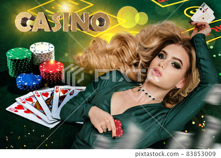 Blonde lady in green dress is showing red chips and aces. Lying on playing table with inscription casino, cards and colorful sparkles. Poker. Close-up Blonde lady in green dress is showing red chips and aces. Lying on playing table with inscription casino, cards and colorful sparkles. Poker. Close-up 83853009