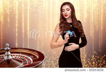 beautiful girl with chips stands on the background of roulette. beautiful girl with chips stands on the background of roulette. 83853638