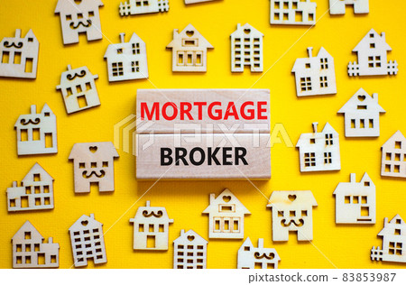 Mortgage broker symbol. Concept words 'Mortgage broker' on wooden blocks near miniature wooden houses. Beautiful yellow background. Business, mortgage broker concept. 83853987