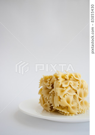 Farfalle cooked farfallini pasta in a shape of square on a white plate. Farfalle cooked farfallini pasta in a shape of square on a white plate. 83855430