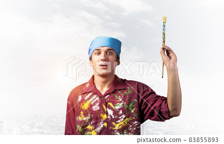 Handsome young painter artist pointing upwards Handsome young painter artist pointing upwards 83855893