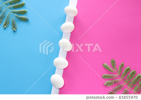 White chicken eggs with leaves on blue and pink background. Easter concept.  83855970