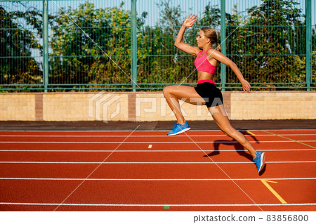 Side view beautiful young woman exercise jogging and running on athletic track on stadium Side view beautiful young woman exercise jogging and running on athletic track on stadium 83856800