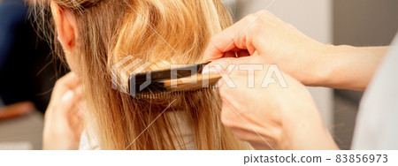 A hairdresser is combing female hairstyling in a hairdressing beauty salon. A hairdresser is combing female hairstyling in a hairdressing beauty salon. 83856973