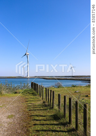 Windmills for electric power production with wooden fence. 83857146