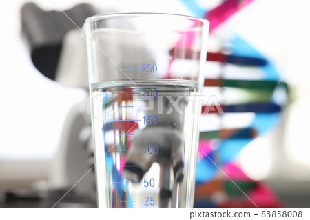 Glass of water standing near dna molecule mockup and microscope in laboratory closeup Glass of water standing near dna molecule mockup and microscope in laboratory closeup 83858008