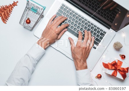 Christmas online store. Gift box red ribbon, trolley and laptop, money in flat lay internet online shopping composition. Xmas shop, top view. Christmas online store. Gift box red ribbon, trolley and laptop, money in flat lay internet online shopping composition. Xmas shop, top view. 83860197