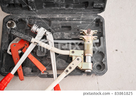 Tools of plumber for clamps the connectors on the pipe. connection heating pipes to white Radiator in a new apartment under construction. Tools of plumber for clamps the connectors on the pipe. connection heating pipes to white Radiator in a new apartment under construction. 83861825