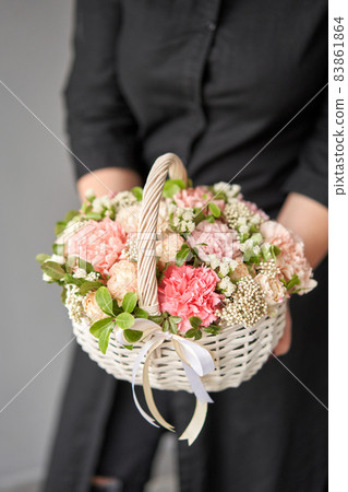 Flower arrangement in Wicker basket. Beautiful bouquet of mixed flowers in woman hand. Handsome fresh bouquet. Small flower shop and Flowers delivery. 83861864