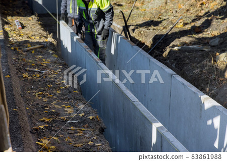 Construction workers installing precast u-shape concrete drain at the reconstruction road Construction workers installing precast u-shape concrete drain at the reconstruction road 83861988