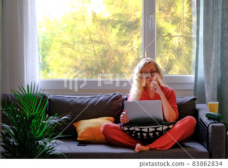 Blonde woman in glasses talking on phone holding her laptop computer. Blonde woman in glasses talking on phone holding her laptop computer. 83862834