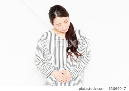 A woman in casual clothes who puts her hand on her stomach 83864947
