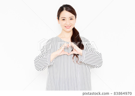 A woman in casual clothes who makes a heart shape by hand 83864970