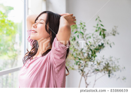 A refreshing woman standing by the window and bathing in the morning light A refreshing woman standing by the window and bathing in the morning light 83866639