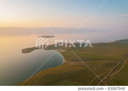 Olkhon Island at sunrise, the largest island in Lake Baikal in eastern Siberia. Shamanka Rock on Baikal lake near Khuzhir at Olkhon island in Siberia, Russia. 83867048