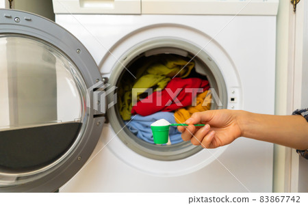 Female hand holds a cap with washing powder. Female hand holds a cap with washing powder. 83867742