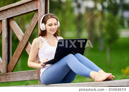 Online learning or teleworking using laptop connected internet via 5g network, young woman does e-learning while visiting public park. Online learning or teleworking using laptop connected internet via 5g network, young woman does e-learning while visiting public park. 83868659